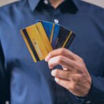Person holding three credit cards, symbolizing finance, security, and e-commerce.